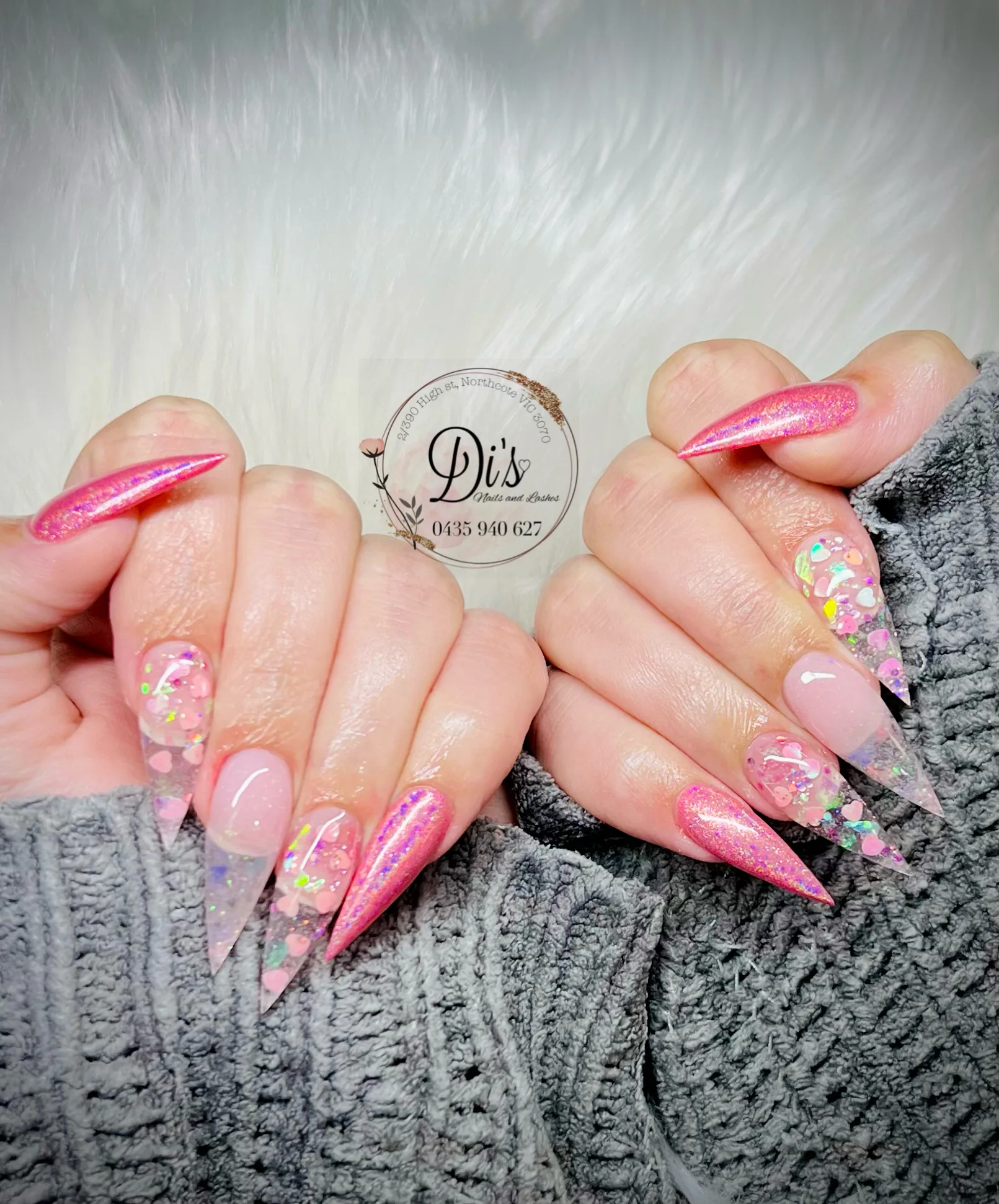 Pink stiletto nails with heart glitter accents on white fur