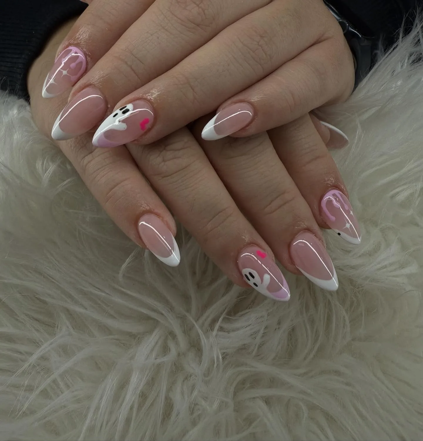Almond nails with crisp white French tips, hand-painted pink ghost characters and tiny hot-pink hearts — on white fur