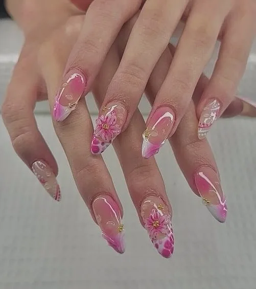 Almond nails in pink-and-white watercolour marble with sculpted 3D pink daisies and gold bead centres